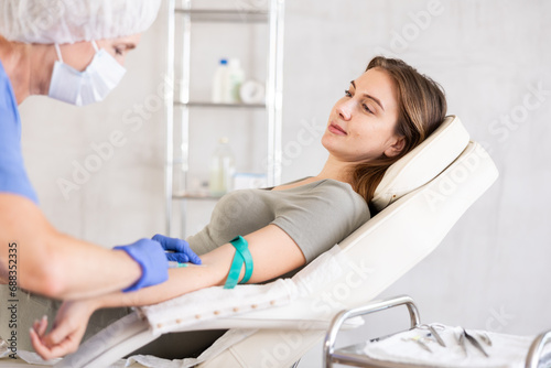 Tableau sur toile Professional elderly doctor in scrub drawing blood from young patient