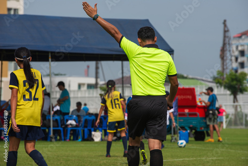 Professional soccer referee on a youth soccer tournament. Seeing girls in the pitch playing a match with lots of intense and passion. photo