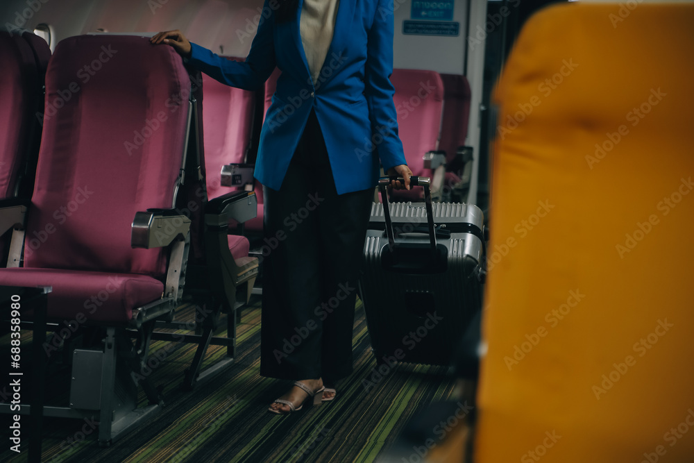 Asian female traveler putting luggage into overhead locker on airplane during boarding. Asian female traveler putting luggage into overhead locker on airplane during boarding.