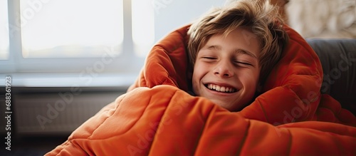 Teenage boy smiling and keeping warm near radiator in cold house during poor heating in winter season. photo
