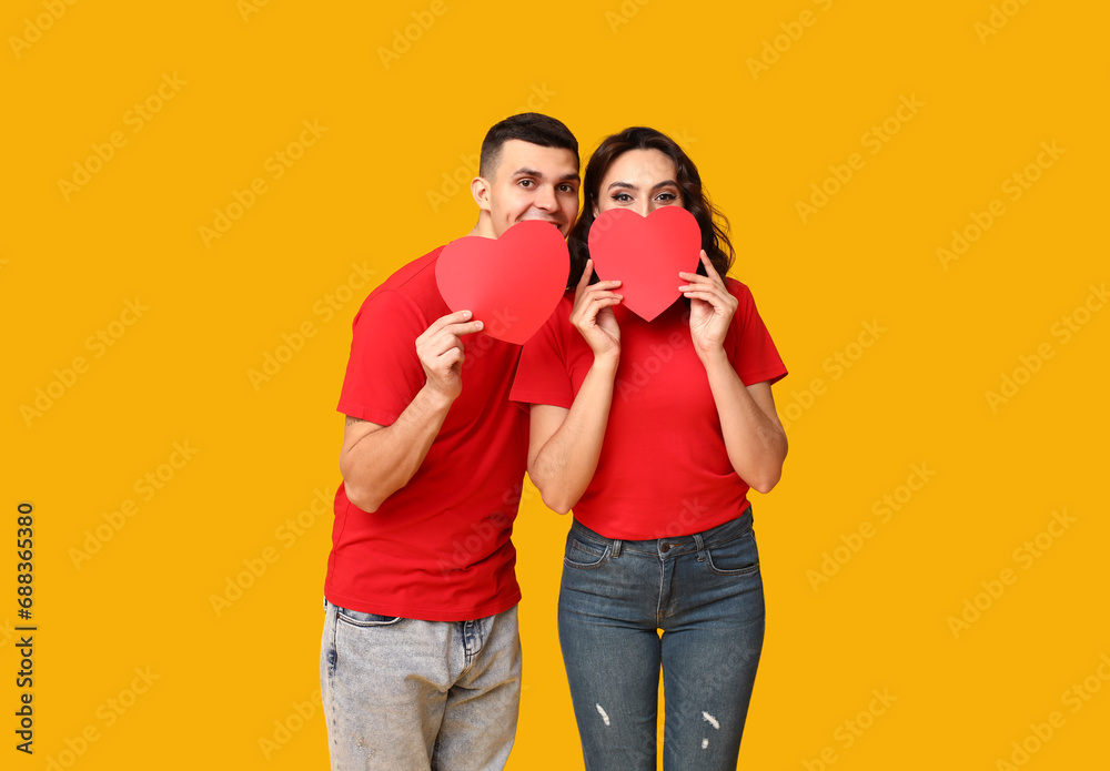 Loving young couple with paper hearts on yellow background. Celebration of Saint Valentine's Day Loving young couple with paper hearts on yellow background. Celebration of Saint Valentine's Day