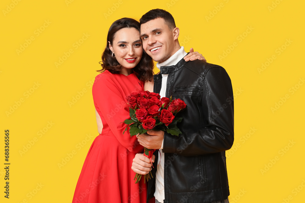 Loving young couple with bouquet of beautiful roses on yellow background. Celebration of Saint Valentine's Day Loving young couple with bouquet of beautiful roses on yellow background. Celebration of Saint Valentine's Day