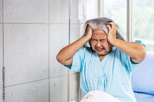 Elderly asian woman sitting on bed suffering from headache and migraine so pain and illness, Stress senior woman sit on bed at hospital or clinic alone, tried, Unhappy Elderly despond concept