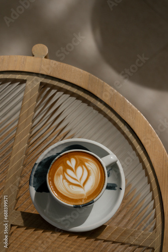 Cup of coffee latte on glass table and beautiful latte art with afternoon light.