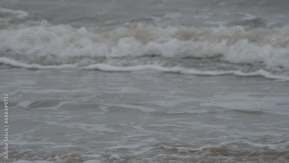 Close up of waves crashing on Formby beach in Merseyside, England on rainy and windy day Close up of waves crashing on Formby beach in Merseyside, England on rainy and windy day