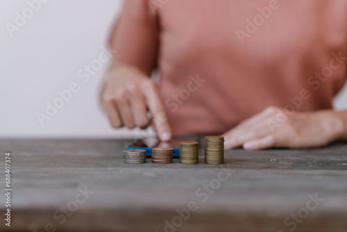 Wallpaper Mural hand placing a coin into a white piggy bank on a table against a pale pink background. Torontodigital.ca