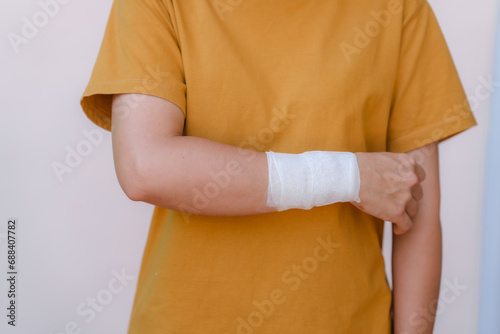 A person in a yellow top has white bandages on their hand and wrist because of a car accident.
