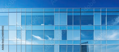 Blue sky mirrored in square windows of contemporary office building.