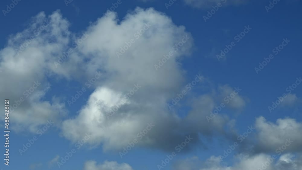 Time lapse of white big clouds moving past blue patches of sky Time lapse of white big clouds moving past blue patches of sky