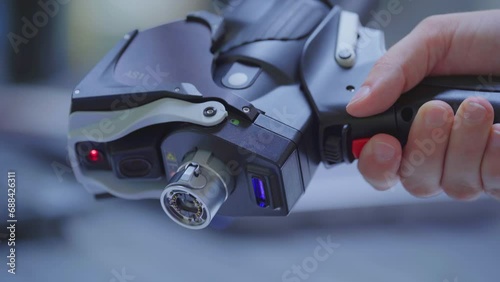 Hand hold futuristic laser scanner and pushes red button. Measure 3D parts - close up. photo