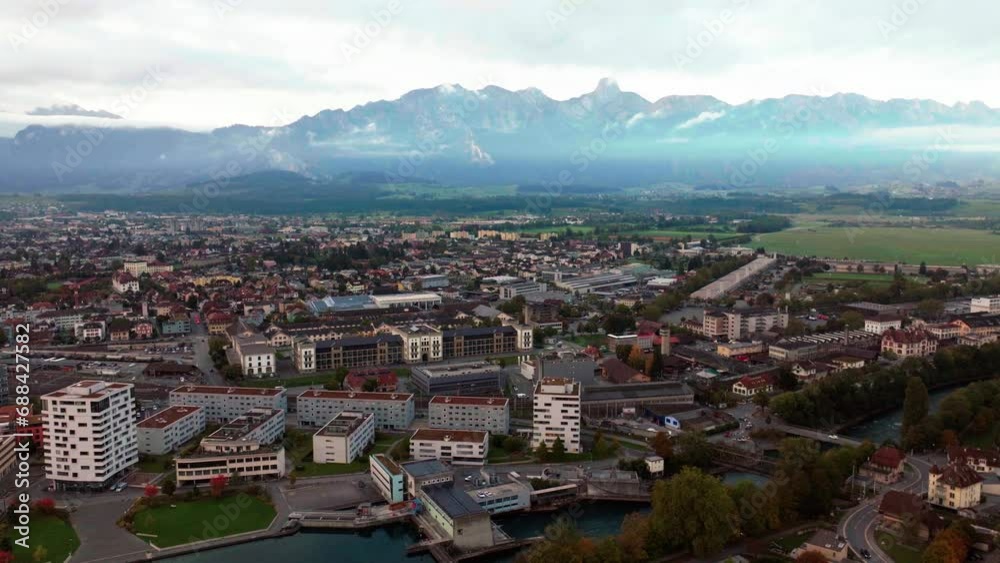 Aerial cinematic drone early cloudy morning Thun Switzerland Swiss lake river downtown city village Bern Interlocken view of Stockhorn Stockhornkette sunrise backwards slowly movement