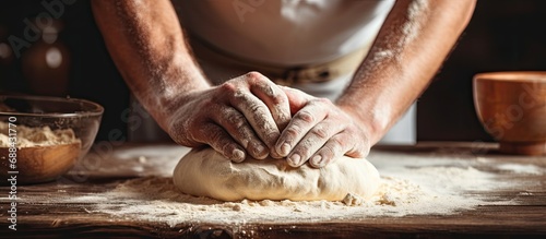 Baker preparing homemade bread on wooden table, hands making dough in close-up view. photo