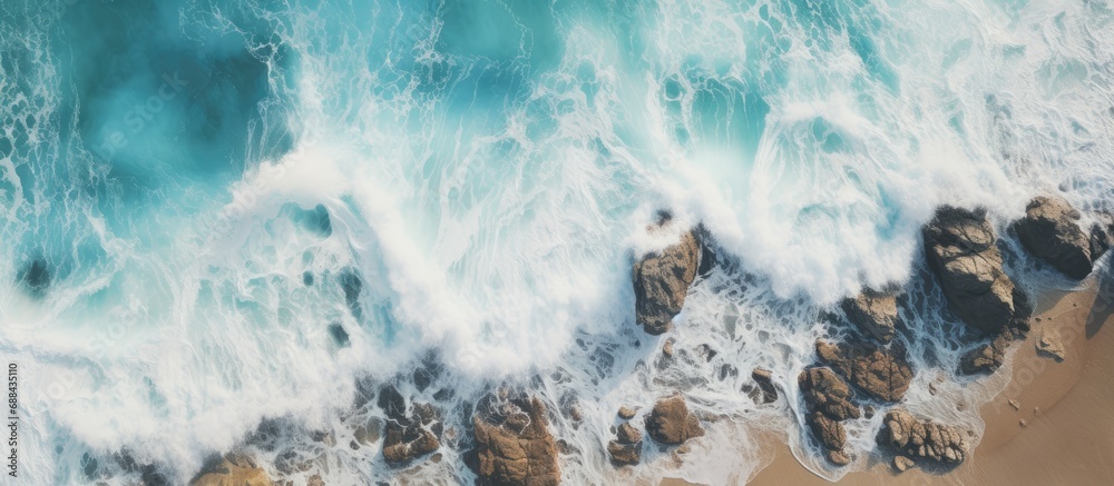 Wedding Cake Rock beach in Sydney captured from above as waves crash on the rocky cliff.