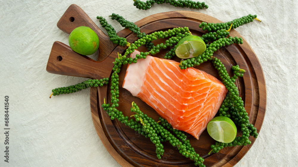 salmon, limes and green peppers on a wooden board
