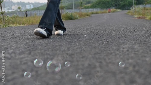 Walking legs of woman. Flying soap bubbles. Walking on the asphalt road. Summer season. Travel summer. Thinking moment..