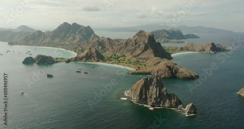 Aerial Backward Beautiful View Of Nautical Vessels In Sea By Tranquil Komodo Island Against Cloudy Sky photo