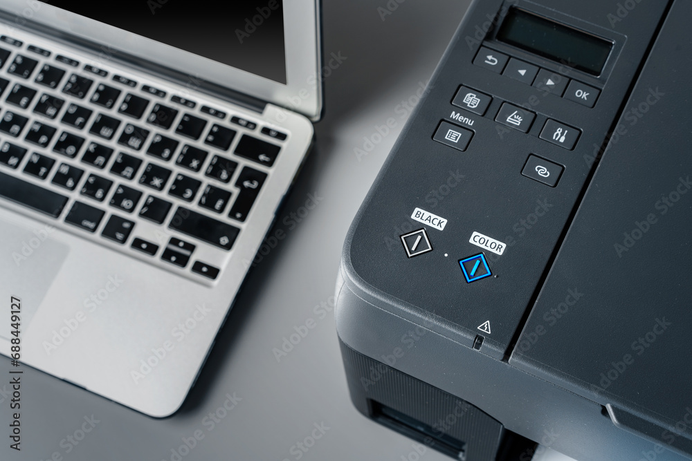 Printer and laptop on grey table in office Printer and laptop on grey table in office