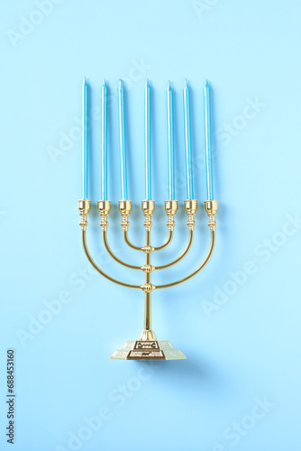 Golden menorah with candles on blue background. Happy Hanukkah concept.