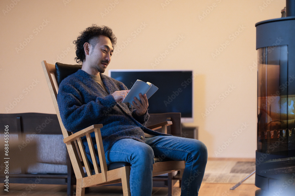 A man relaxes in an easy chair by the fireplace in his room