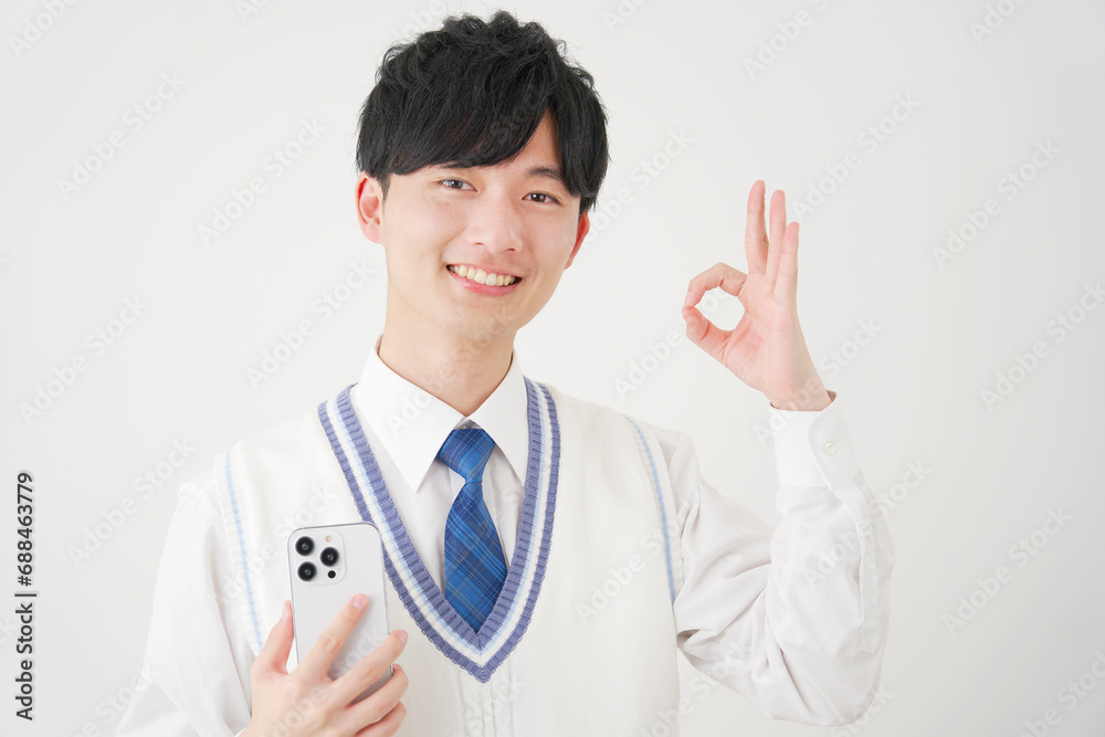 スマートフォンを持ってOKサインをする男子高校生 白背景 スマートフォンを持ってOKサインをする男子高校生 白背景