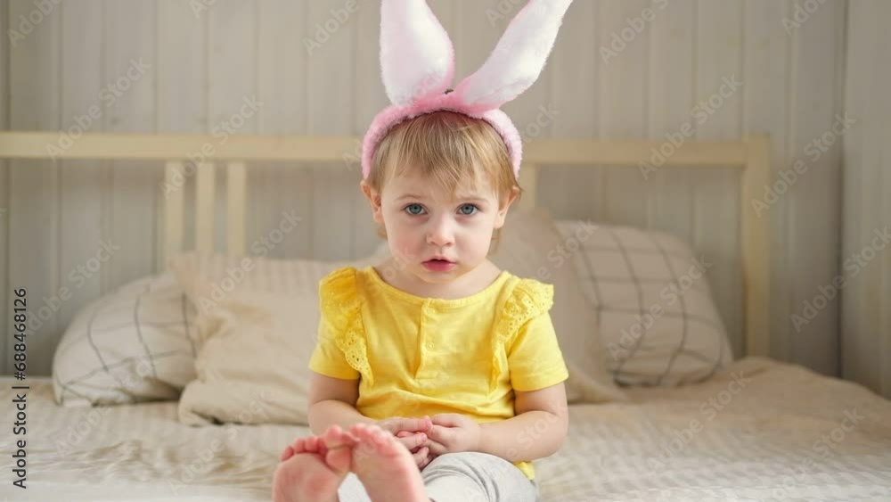 Baby girl with bunny ears. Cute funny baby play Easter eggs at home. Child playing colorful eggs indoors. Spring. Little kid celebrating Easter with traditional symbol of holiday and religion concept. Baby girl with bunny ears. Cute funny baby play Easter eggs at home. Child playing colorful eggs indoors. Spring. Little kid celebrating Easter with traditional symbol of holiday and religion concept.