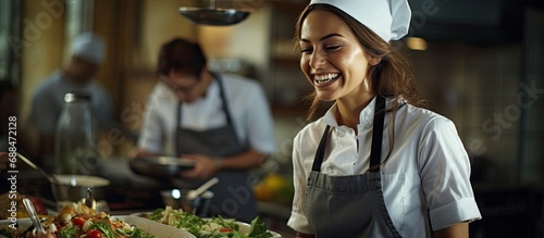 Smiling chef or waitress in apron and toque standing in restaurant photo