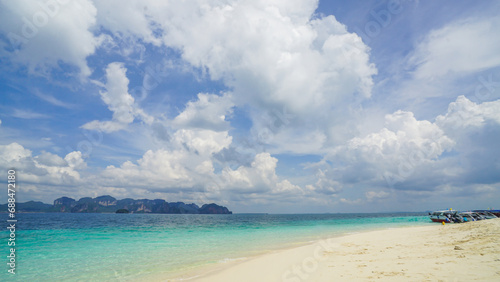 Clear tropical water and cumulus clouds on the horizon  Thailand. Smooth white sand beach on blue sea water and white wave under white fluffy clouds and pastel blue sky background
