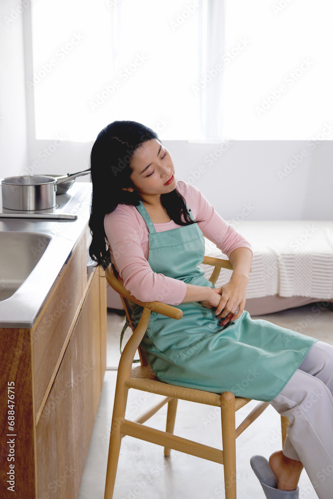 キッチンの椅子で休んでいる女性 キッチンの椅子で休んでいる女性