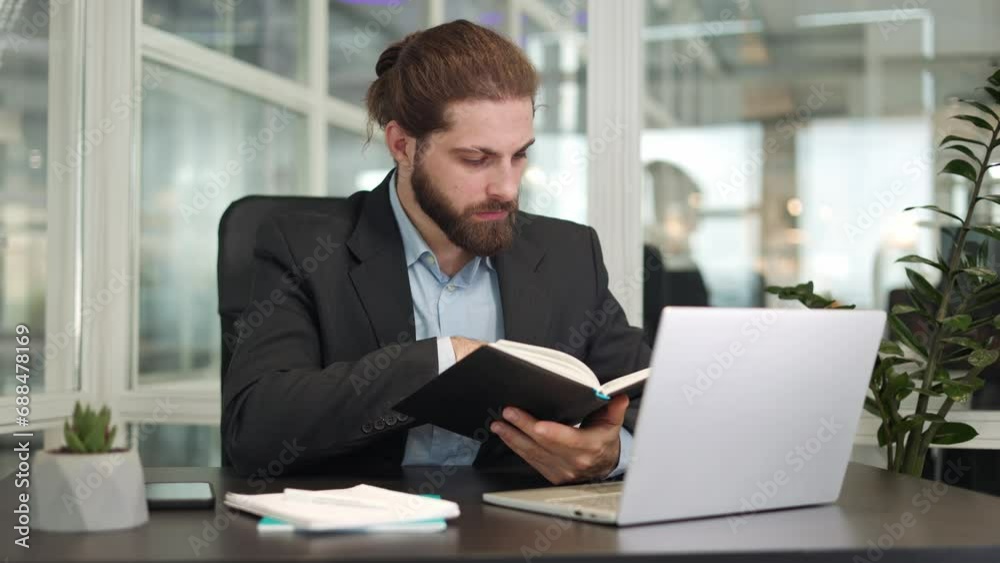 Portrait of handsome smart caucasian businessman reading information from personal notebook while having video call on wireless laptop indoors. Busy bearded male discussing work process in office. Portrait of handsome smart caucasian businessman reading information from personal notebook while having video call on wireless laptop indoors. Busy bearded male discussing work process in office.