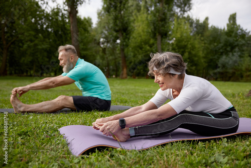 Happy senior couple doing yoga stretching exercise outdoors