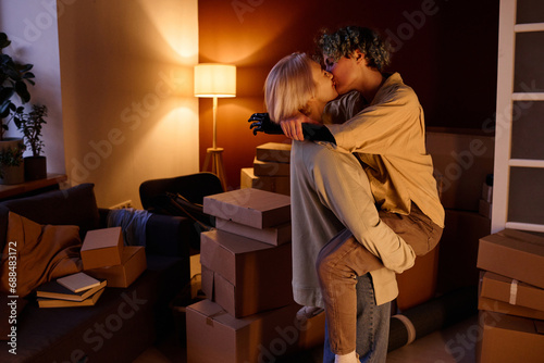 Young lesbian couple happy to move, they kissing among boxes in the room photo