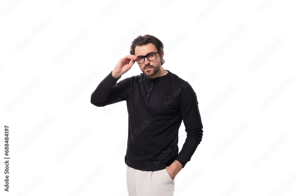 Naklejka premium well-groomed young caucasian brunette man with a beard put on glasses for the correction of granulation