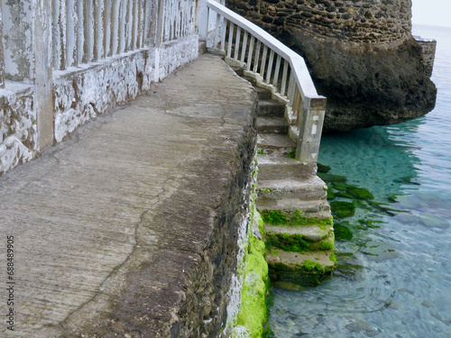 Stairs to the sea. A stone staircase with railings leads into the water. A staircase with stone steps covered with sea mud leads to the seashore.