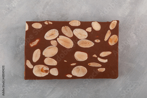 Chocolate Turron with almonds on grey textured background, top view. Traditional Spanish Turron with cocoa, milk chocolate and nuts