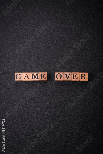 The inscription game over on wooden cubes on a dark concrete background