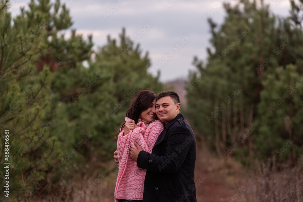 Close-up portrait of couple hugging in green coniferous forest. Young man tactilely wrapped woman Close-up portrait of couple hugging in green coniferous forest. Young man tactilely wrapped woman
