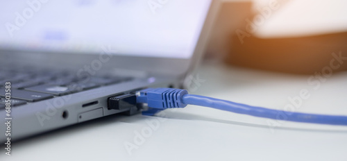 close up on laptop port interface with blue an cable connected to transfer bandwidth and usage internet data to global network for internet technology transmission service concept photo