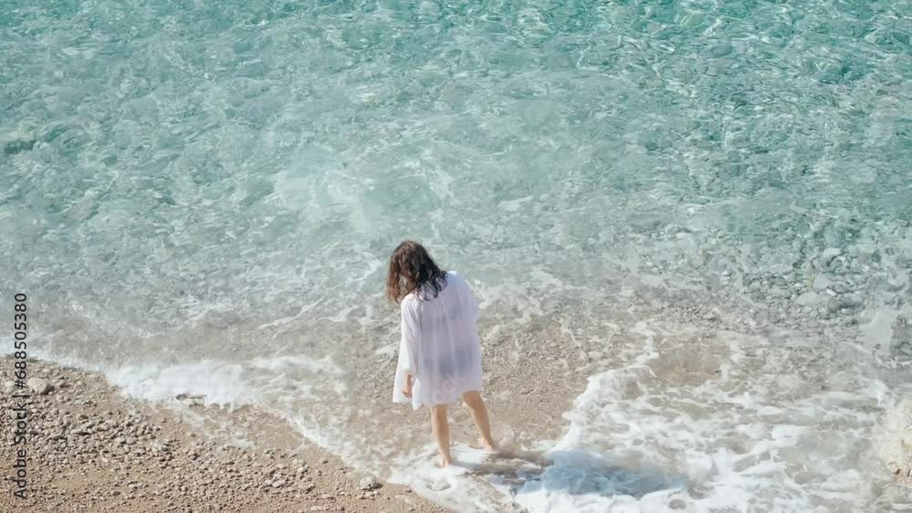 Aerial view of a young woman walking the beach by the clear azure water. The Mediterranean Sea in Turkey.