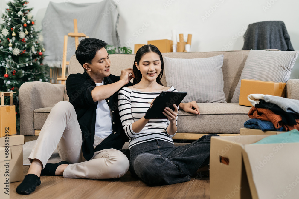 Young couple relaxing sitting on the sofa using the computer laptop around cardboard boxes, very happy moving to a new house. Young couple relaxing sitting on the sofa using the computer laptop around cardboard boxes, very happy moving to a new house.