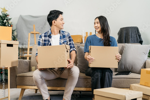 Successful young couple is moving to a nice new place, around boxes with their belongings. The room is very bright and bright, they are wearing casual clothes.