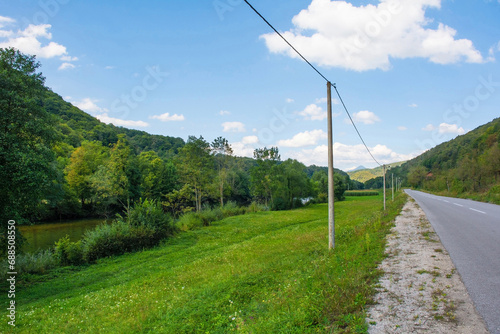A country road follows the course of the River Una just north of Martin Brod, Bihac, in the Una National Park. Una-Sana Canton, Federation of Bosnia and Herzegovina. Early September