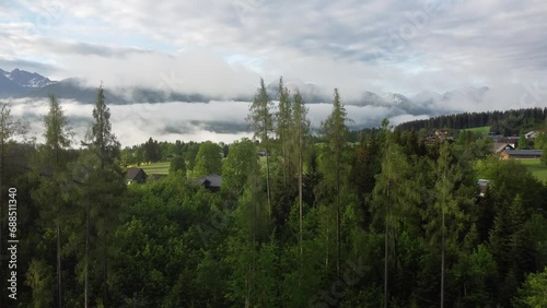 4K drone shot of beautiful misty sunrise at Ramsau am Dachstein, Styria, Austria. Lush green fields and guesthouses at the foot of Dachstein Glacier, popular area for Alpine skiing and snowboarding. photo