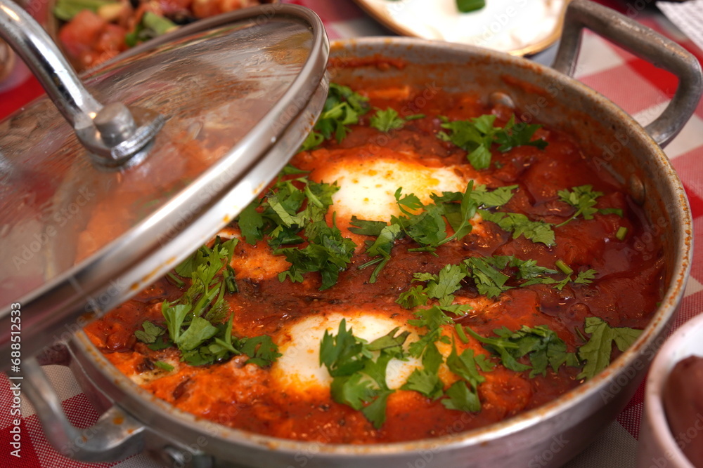 shakshuka poached eggs in a delicious chunky tomato and bell pepper sauce made in a pot with parsley sprinkled on top