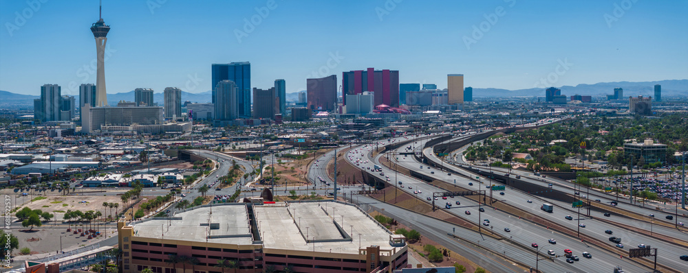 Elevated view of Las Vegas skyline featuring the Stratosphere Tower, high-rises with glass facades, and bustling traffic under a clear blue sky, highlighting the city's vibrancy.