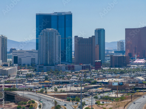 Aerial view of Las Vegas cityscape with modern skyscrapers, diverse architecture, bustling streets, and mountains under a clear blue sky, showcasing urban vibrancy and design.