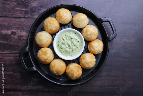 Paniyaram are savory balls made using fermented rice and urad dal batter along with tempered onion and spices. Also known as Paddu, Ponganalu, Kuli, bugga, and appe. served with coconut chutney photo