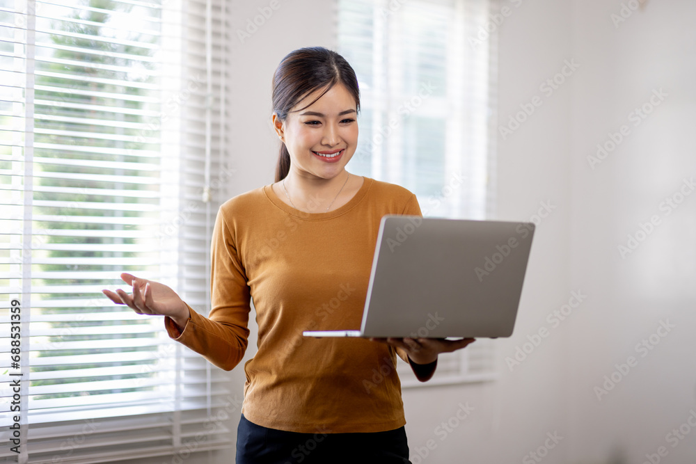 Portrait of young modern business woman standing holding laptop and looking at camera with happy smile, isolated on gray Portrait of young modern business woman standing holding laptop and looking at camera with happy smile, isolated on gray