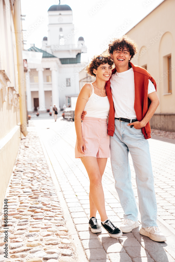 Young smiling beautiful woman and her handsome boyfriend in casual summer white t-shirt and jeans clothes. Happy cheerful family. Female having fun. Couple posing in the street background. Walking