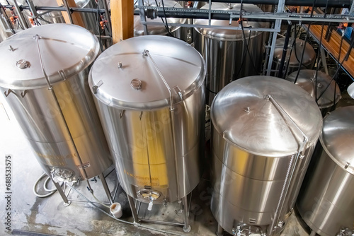 High angle view of some shiny metal tanks and pipework in a beer processing facility for the fermentation and brewing of beer