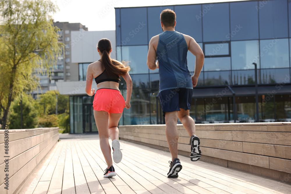 Healthy lifestyle. Couple running outdoors on sunny day, low angle view